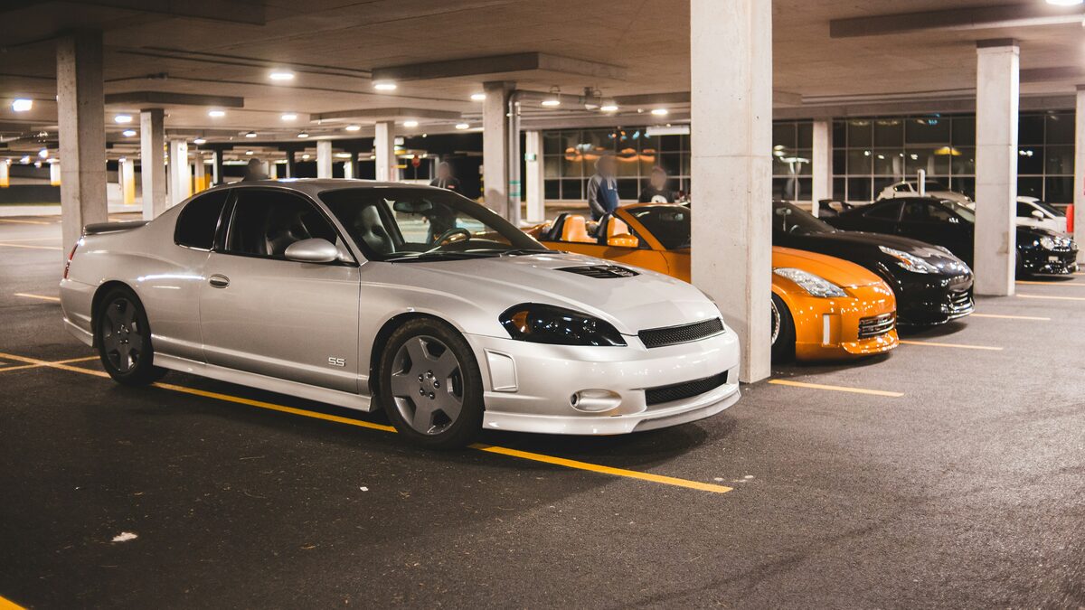 The original photo of a silver coupe in a multi-storey car park at night, with other cars and concrete pillars around it